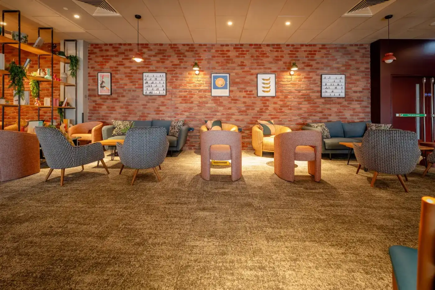 Interior of a Heathrow Terminal 3 lounge with brick feature wall, armchairs and casual seating